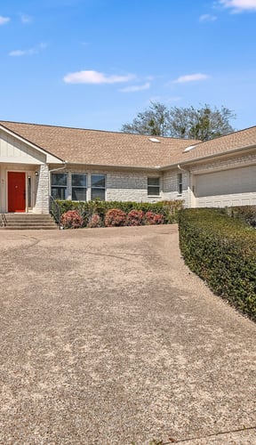 Home exterior with red door and landscaped garden