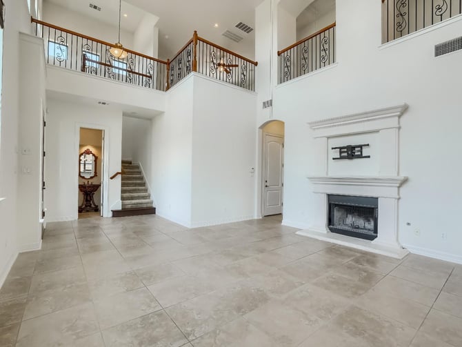 Living room with a double-height ceiling, floor-to-ceiling windows, and an elegant fireplace