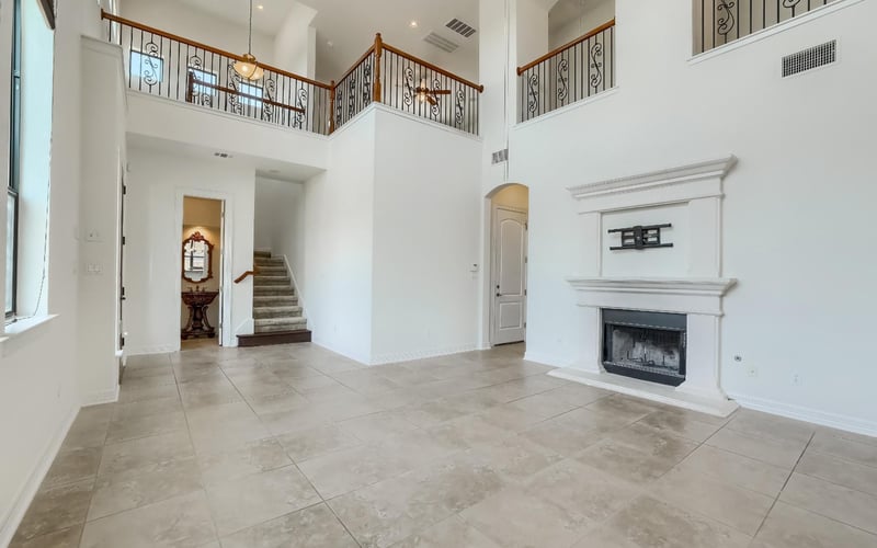 Living room with a double-height ceiling, floor-to-ceiling windows, and an elegant fireplace