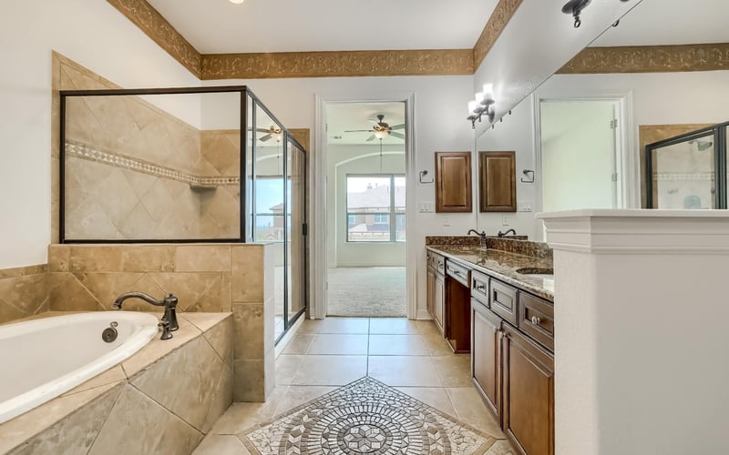 A modern bathroom with a large oval bathtub, sleek glass shower, and polished concrete walls, featuring a minimalist white vanity and industrial-style lighting