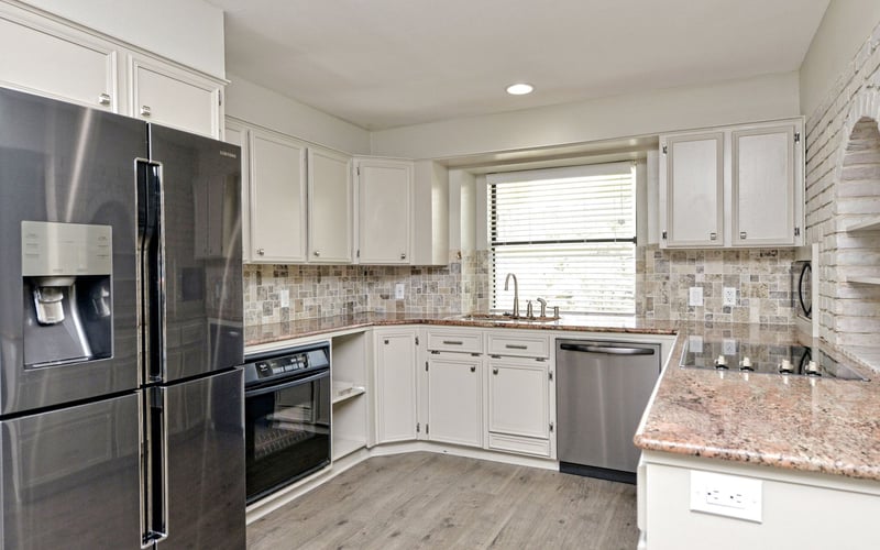 Modern kitchen with white cabinetry, stainless steel appliances, granite countertops, and tile backsplash
